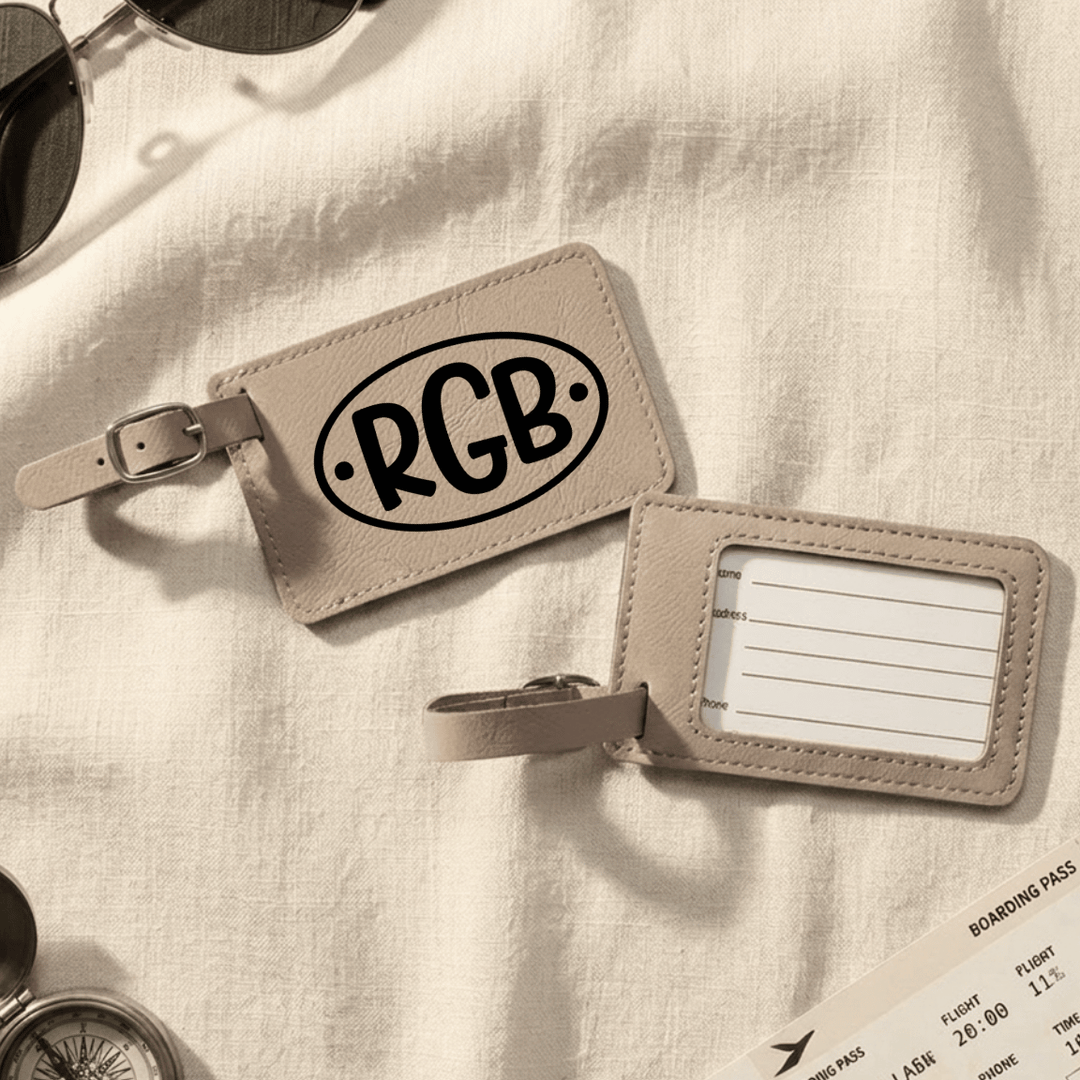 Front and back of light brown luggage tags on a light fabric background with sunglasses and a boarding pass.