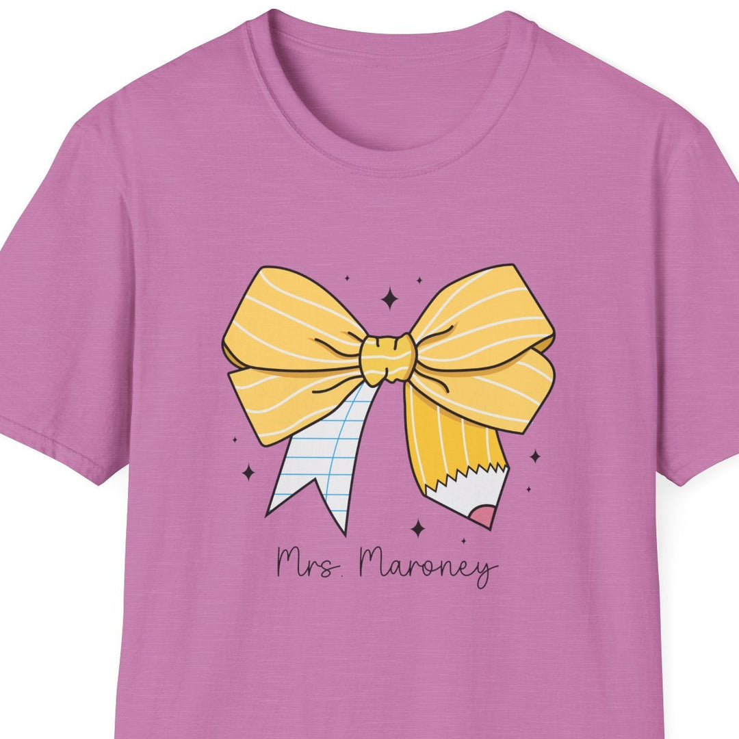 A pink short-sleeve crewneck t-shirt featuring a graphic of a yellow striped bow, a pencil, and the text 'Mrs. Maroney' on the front, displayed against a solid white background.