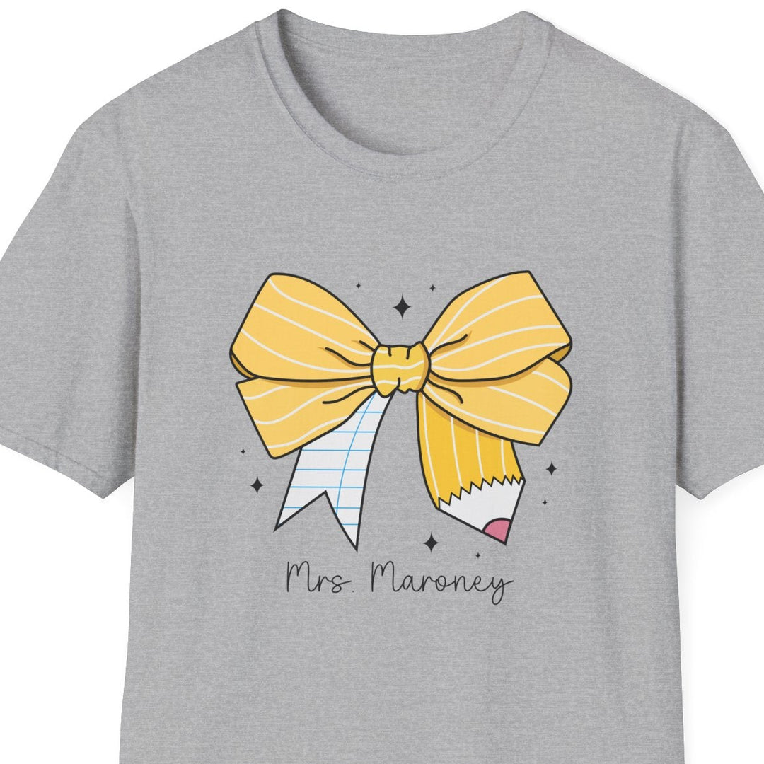 A light gray heather crewneck t-shirt featuring a cartoon graphic of a yellow striped bow and pencil with the text 'Mrs. Maroney' printed below it.