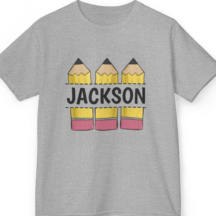 A heather gray short-sleeve t-shirt with a custom graphic print featuring three yellow pencils with pink erasers and the name 'JACKSON' printed across them in black block letters.