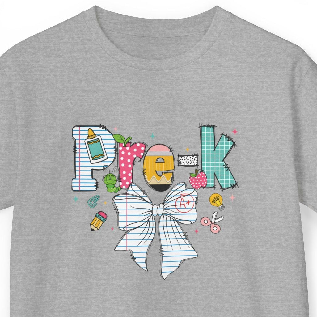 A heather gray short-sleeve t-shirt with a colorful graphic on the chest spelling 'Pre-K' using various doodle-style icons, including a yellow pencil, pink polka dots, a bow tie, and a paintbrush, shown on a plain white background.