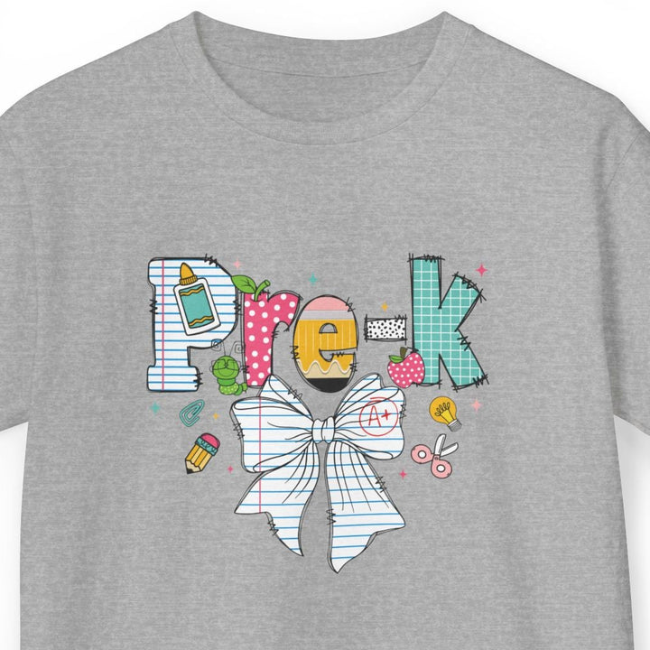 A heather gray short-sleeve t-shirt with a colorful graphic on the chest spelling 'Pre-K' using various doodle-style icons, including a yellow pencil, pink polka dots, a bow tie, and a paintbrush, shown on a plain white background.