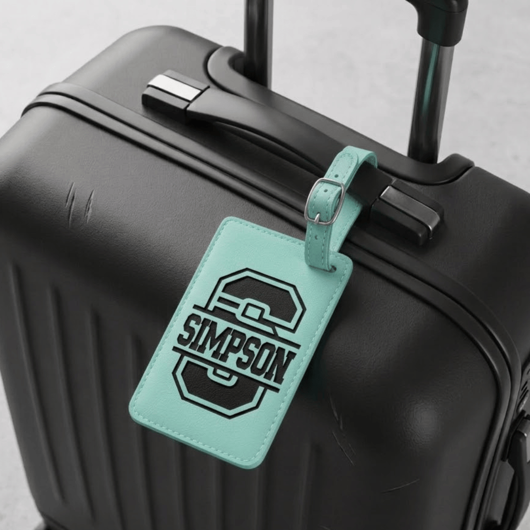 Black suitcase with a teal luggage tag featuring the engraved monogram 'Simpson'.