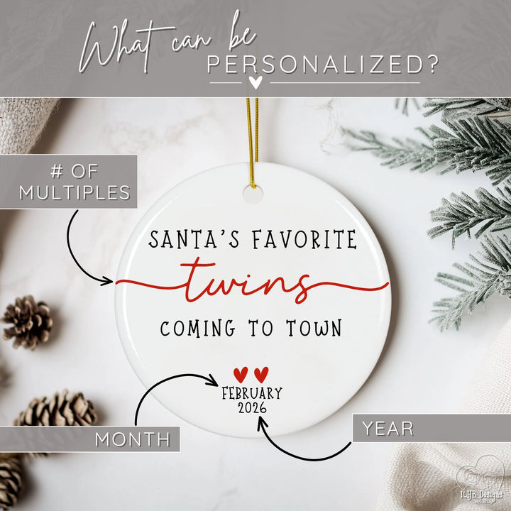 Personalizable Christmas ornament with text 'Santa's Favorite Twins Coming to Town' on a white background with pinecones and branches. Graphic showing what part of ornament can be personalized. The number of multiples, month, and year can be personalized on this round white ceramic Christmas ornament with “Santa’s Favorite Twins Coming to Town” with 2 small red hearts and the month and year due date for babies. With classic black lettering, red accent hearts, and a simple elegant twins word design accented 