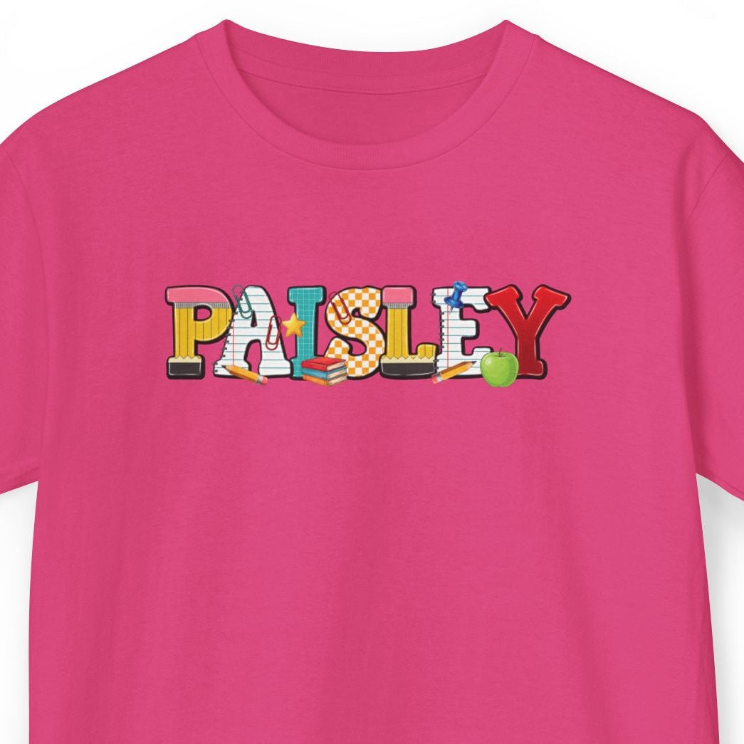 A bright pink short-sleeve t-shirt with a colorful graphic text print reading 'Paisley' across the chest, displayed on a clean white background.