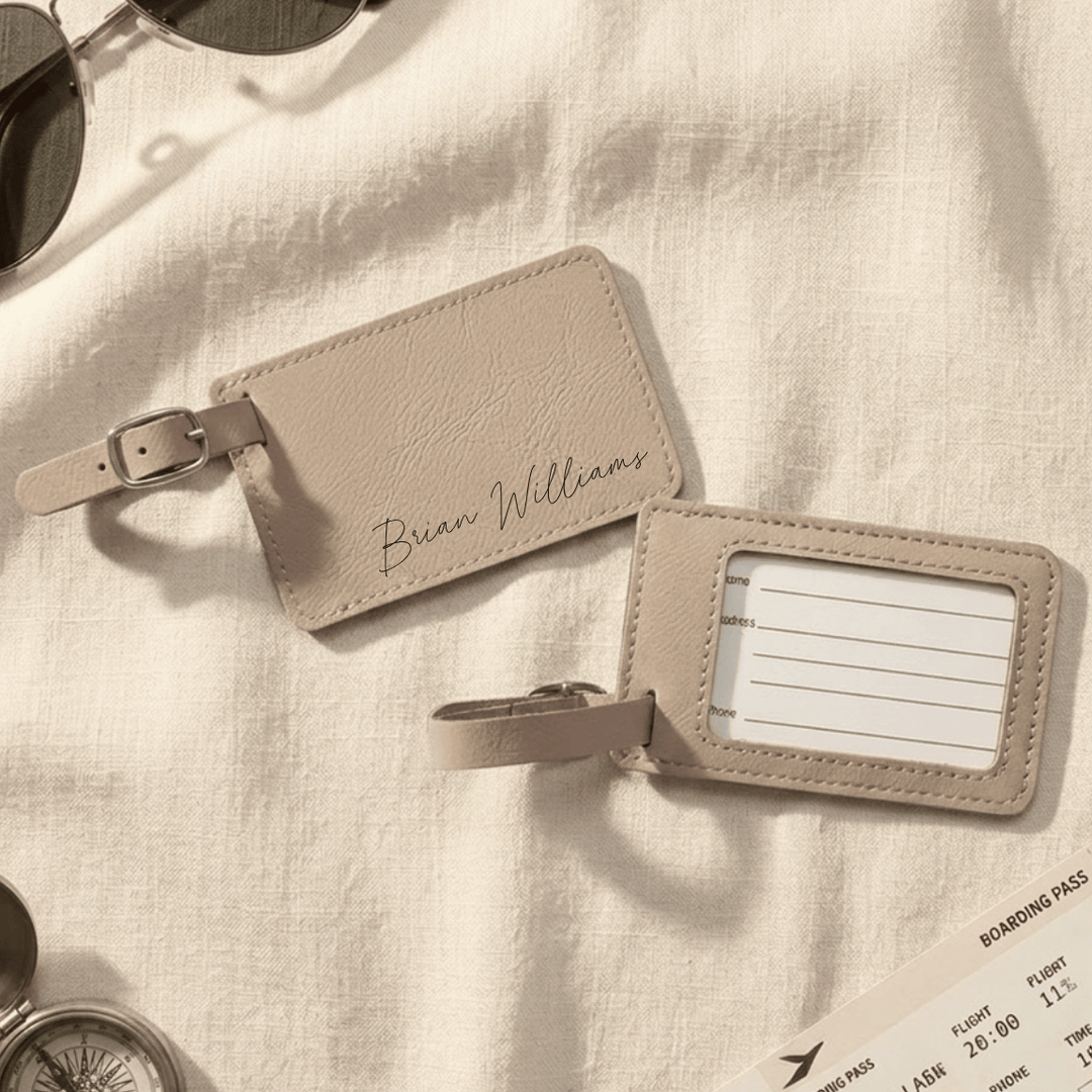 Beige leather luggage tag with name engraving on a light fabric background