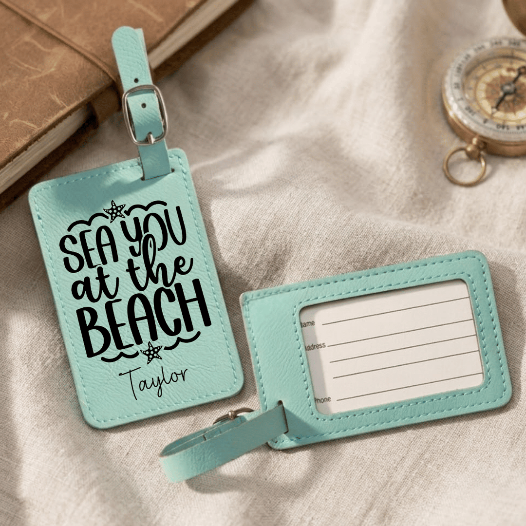 Two turquoise luggage tags with text on a beige fabric background