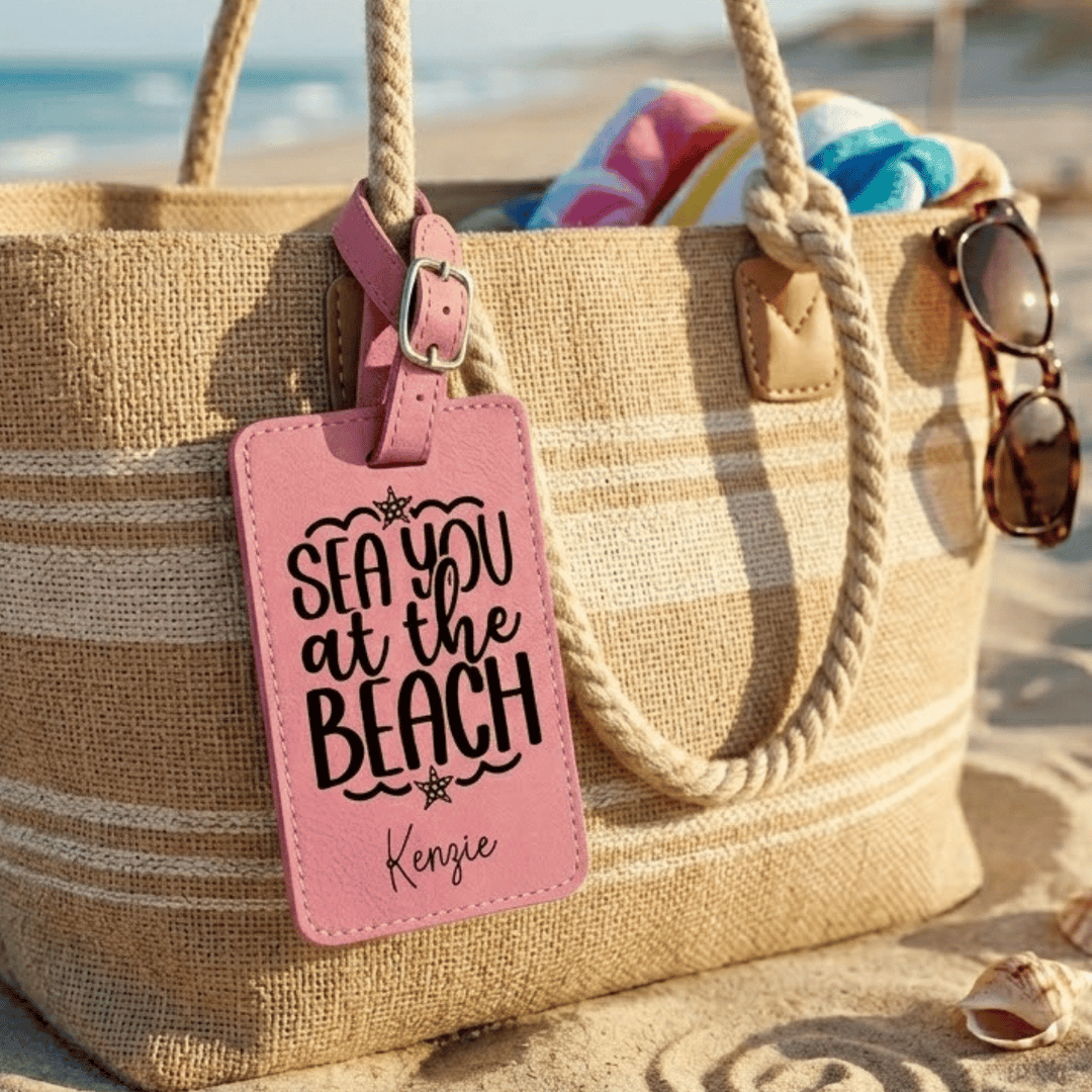 Beach bag with pink 'Sea you at the Beach' tag on a sandy background