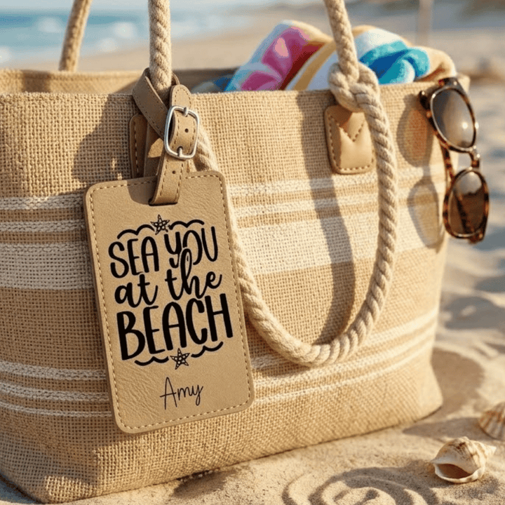 Beach bag with 'Sea you at the Beach' tag on sand