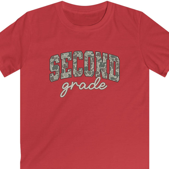 A red short-sleeve crewneck t-shirt featuring a graphic on the chest that reads 'SECOND grade' in arched camouflage letters with white script underneath, displayed on a solid white background.
