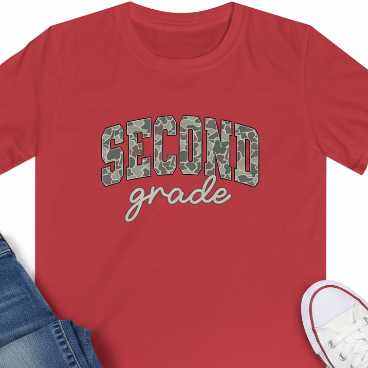 A red short-sleeve crewneck t-shirt featuring the text 'SECOND grade' printed on the chest. 'SECOND' is in a green camouflage pattern, and 'grade' is in a light gray script font.
