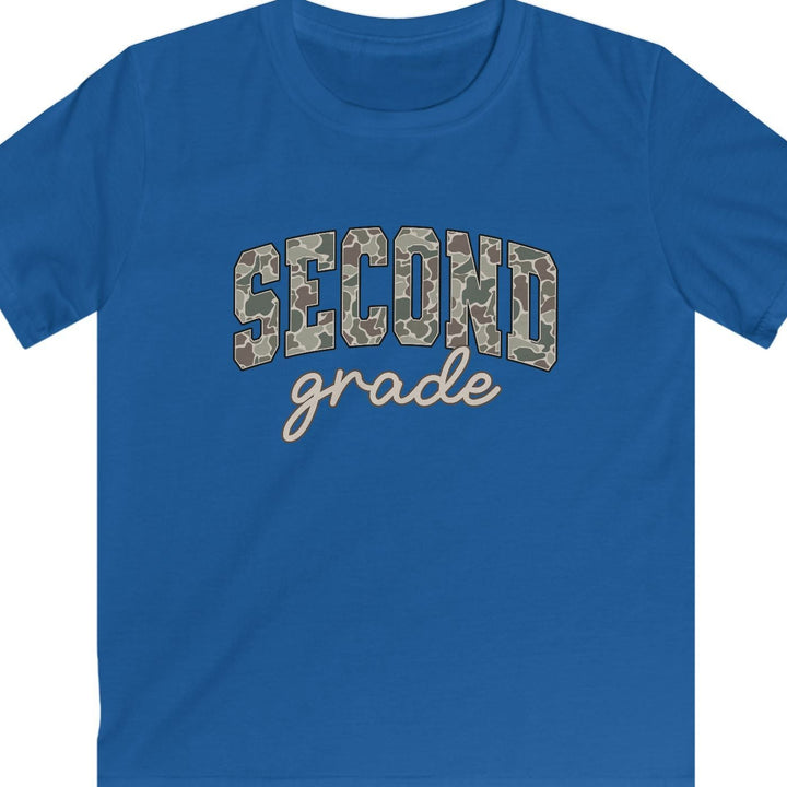 A royal blue short-sleeve t-shirt with 'SECOND grade' printed on the chest. The word 'SECOND' is in arched block letters filled with a tan and brown camouflage pattern, while 'grade' is written below in a light beige cursive script.