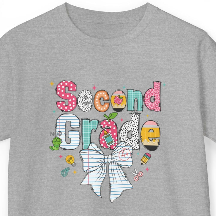 A heather gray short-sleeve t-shirt with a colorful 'Second Grade' graphic on the chest, featuring a white bow, polka dots, and school-themed doodles, shown against a plain white background.