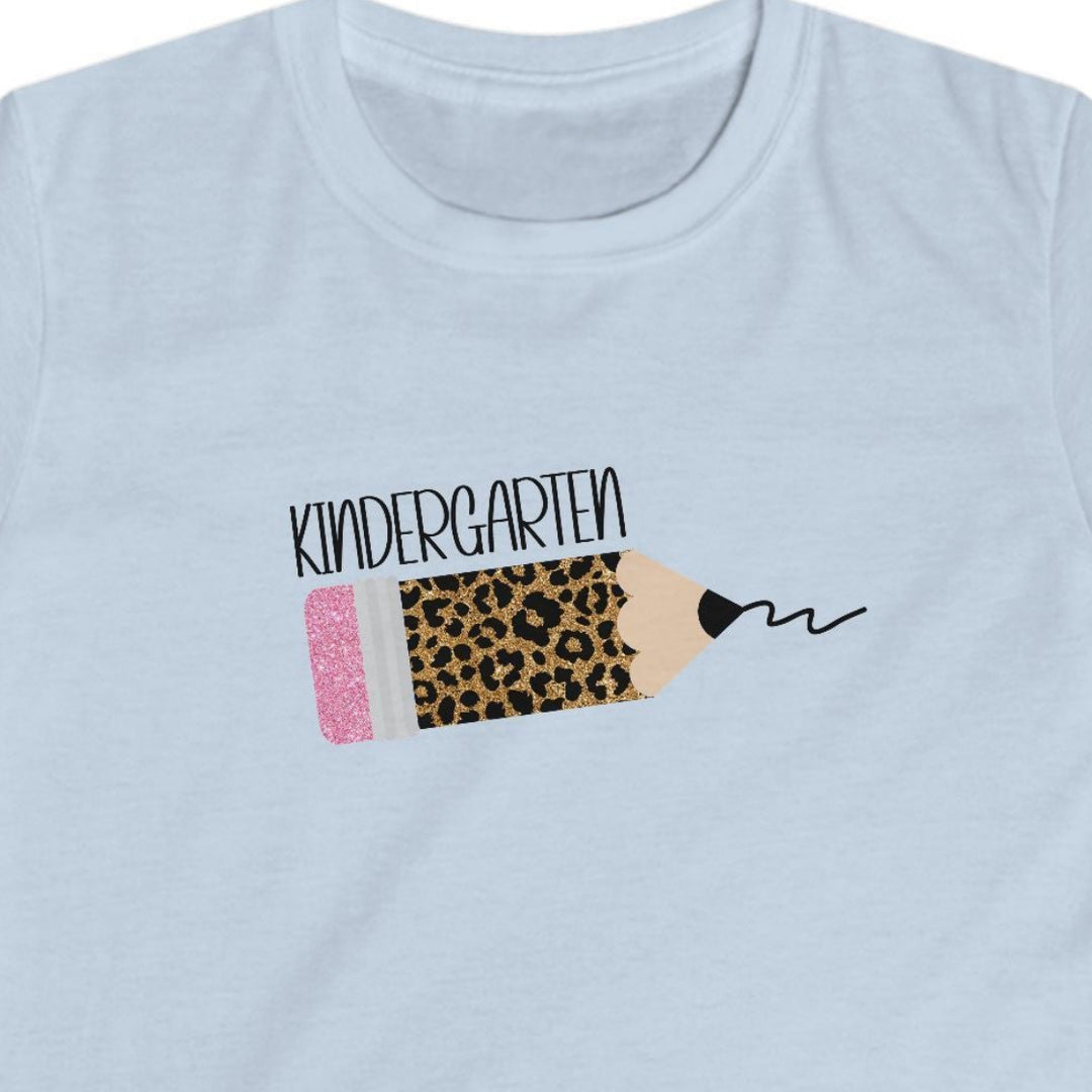 A light blue short-sleeve kids' t-shirt with a leopard pencil graphic slanted on the chest featuring black text above it that says 'kindergarten', displayed on a clean white background.