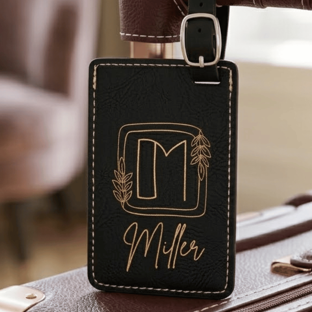 Black leather luggage tag with gold lettering attached to a suitcase.