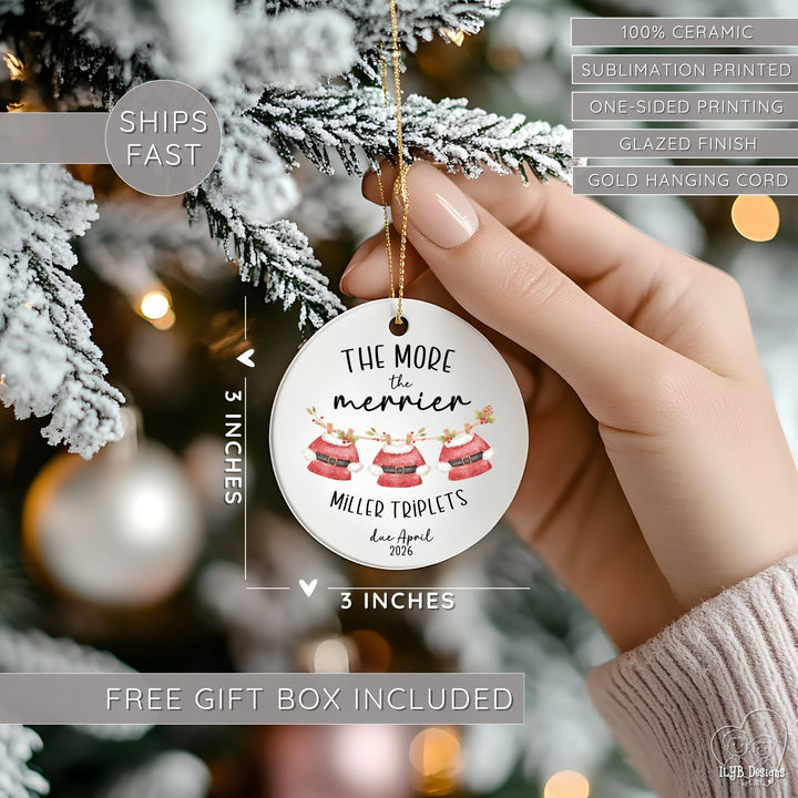 Hand hanging "The more the merrier" ornament on a Christmas tree and showing dimensions of the ornament in perspective next to the hand. Ornament dimensions are 3 inches x 3 inches. Other features are highlighted: 100% ceramic, sublimation printing, one-sided print, glazed finish, gold hanging cord, free gift box included, ships fast.