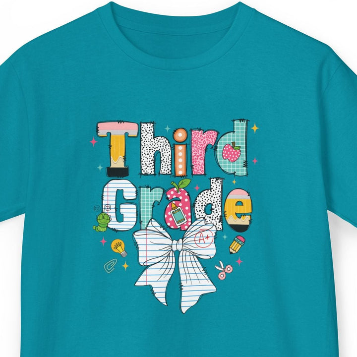 A teal short-sleeve t-shirt with a colorful 'Third Grade' graphic on the chest, featuring a white-and-black checkered bow illustration, displayed on a clean white background.