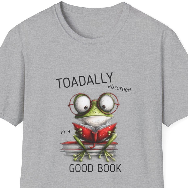 A light gray heather crewneck t-shirt featuring a cartoon graphic of a green frog wearing glasses and reading a red book, with the text 'TOADALLY absorbed in a' above and 'GOOD BOOK' below.
