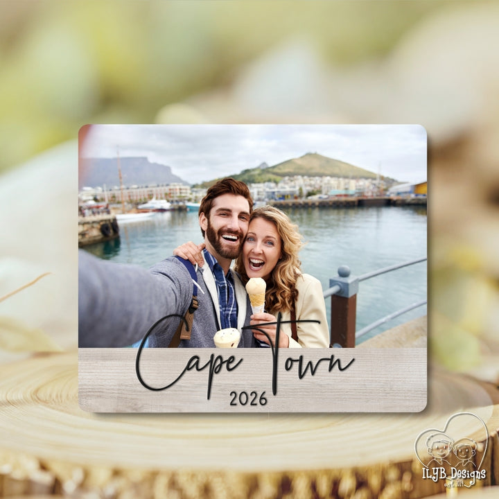 Couple taking a selfie with a scenic background of Cape Town, 2026, on a wooden surface.