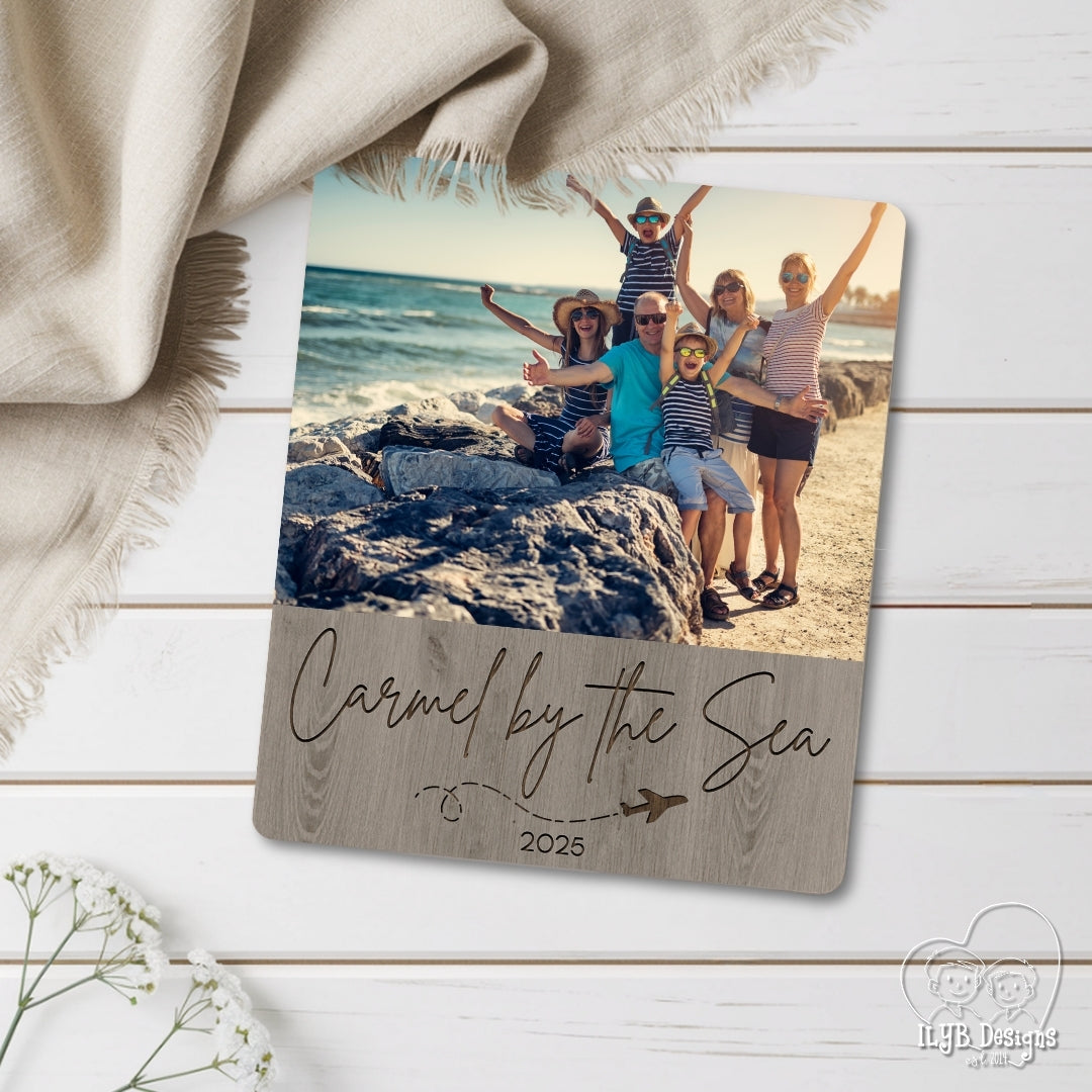 Photo plaque with family photo on beach and 'Carmel by the Sea 2025' text, placed on a wooden surface.