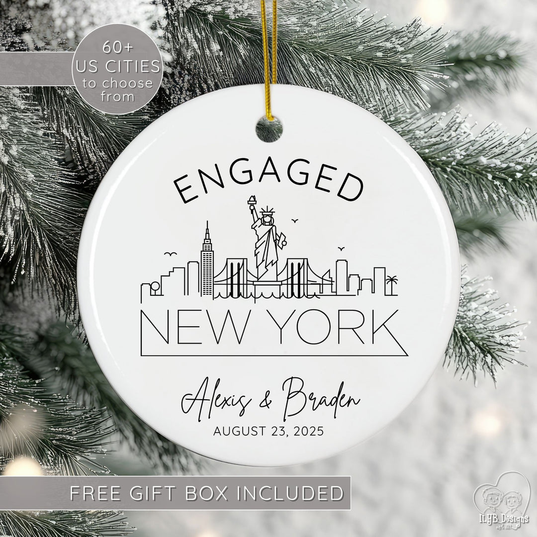 Engagement ornament with black and white line drawing of New York US city skyline with name of city in a thin modern print font below skyline. Above city skyline is word "engaged" slightly curved to match the shape of the round ceramic ornament. Under the US city skyline drawing is the engaged couples names in a modern script font and underneath that is their personalized engagement date.