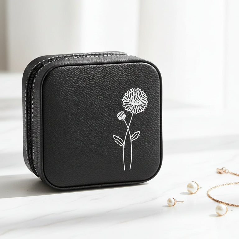 Small black textured zippered jewelry case with a metallic silver floral line drawing engraved.