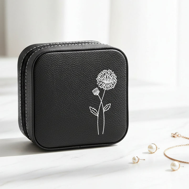 Small black textured zippered jewelry case with a metallic silver floral line drawing engraved.