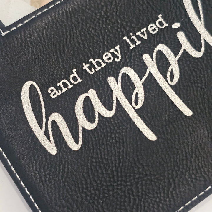 Close-up of a black faux-leather picture frame with white stitching and the phrase &