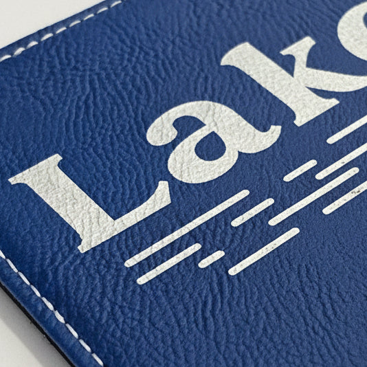Close-up of a blue faux-leather frame with metallic silver engraved text reading &