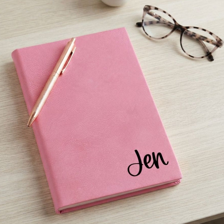 A pink hardcover journal with the name &