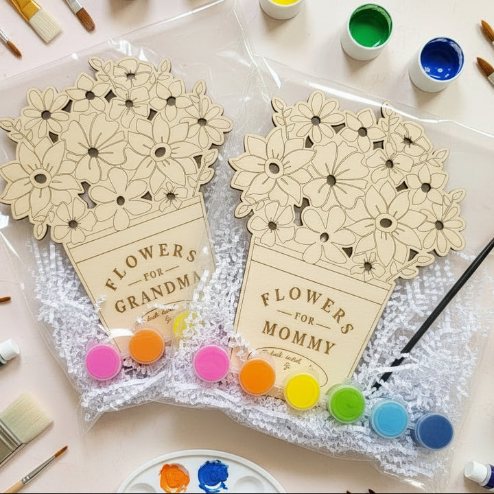 Two wooden floral gift sets in clear plastic bags on a white background. Each set includes a wooden flower arrangement with engraved text reading &