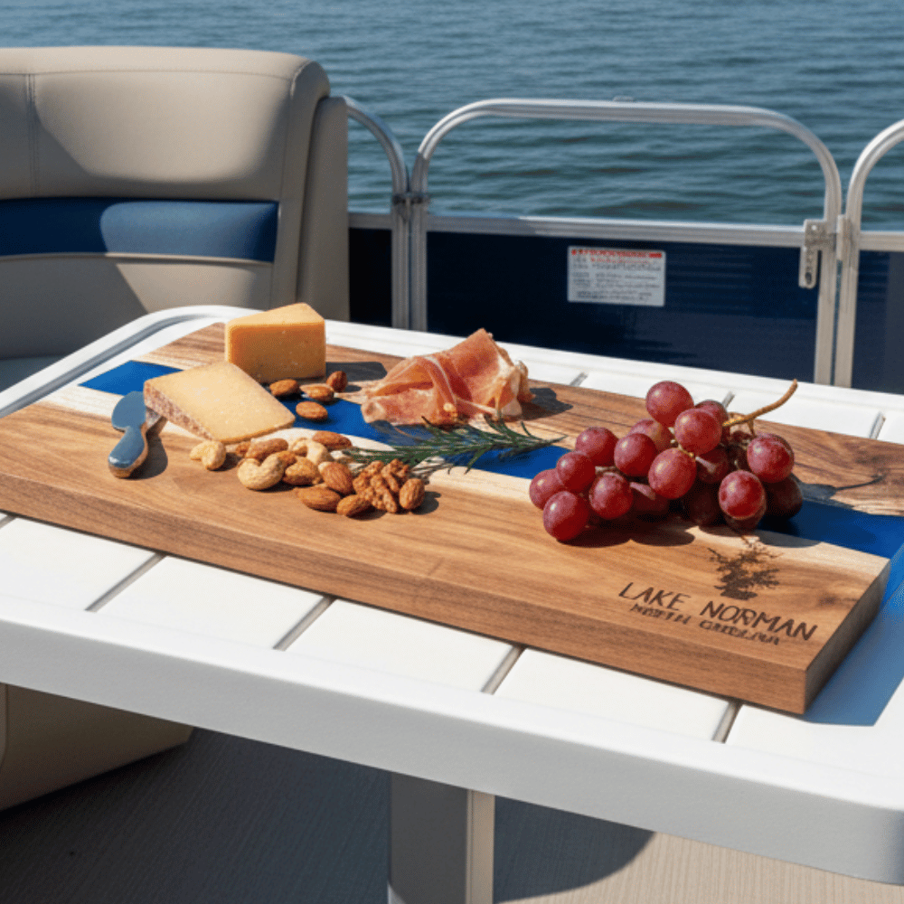 Table on a boat with a wooden cutting board and food, set against a lake backdrop. Bottom right corner of charcuterie board is engraved with a custom lake name and lake silhouette.