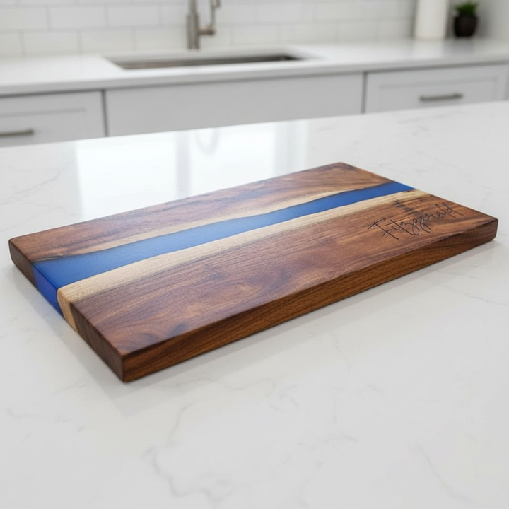 Wooden cutting board with blue resin inlay on a kitchen counter and a last name engraved in the bottom right corner