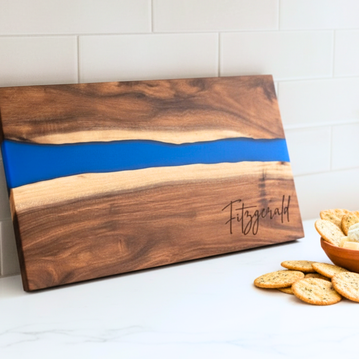 Wooden cutting board with blue resin inlay on a kitchen counter