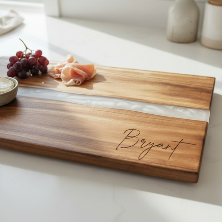 wooden charcuterie board on a kitchen counter with fruits and cheese and an engraved name in the bottom right corner of the board