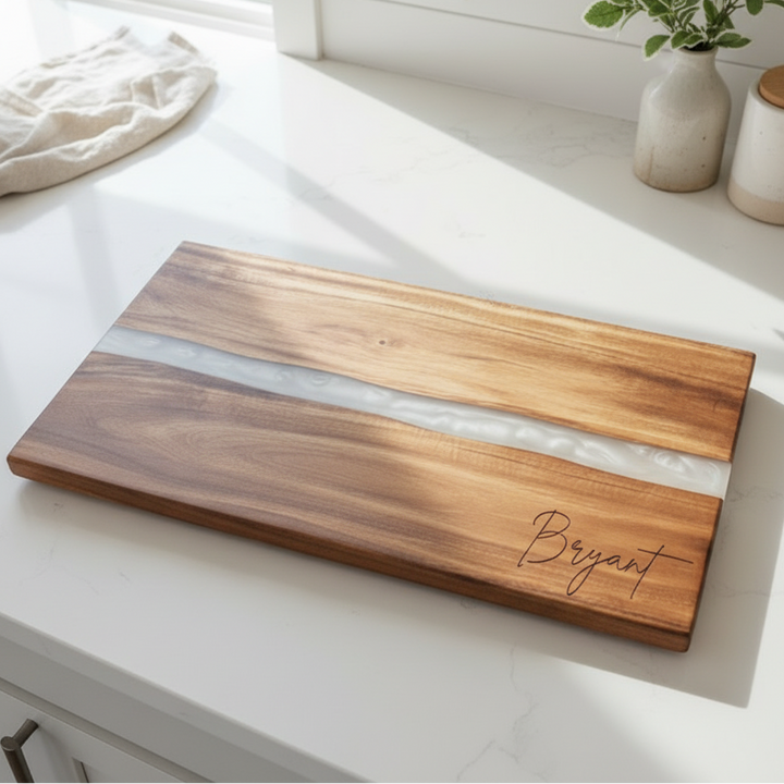 Wooden cutting board with white resin inlay on a kitchen counter, engraved with last name 'Bryant' in bottom right corner.