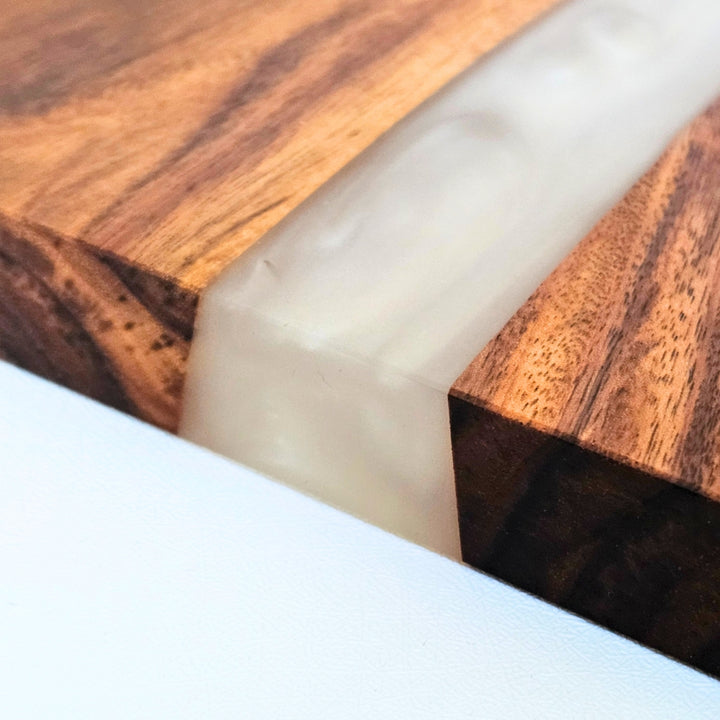 Close-up of a wooden charcuterie board with pearl white resin inlay in the middle