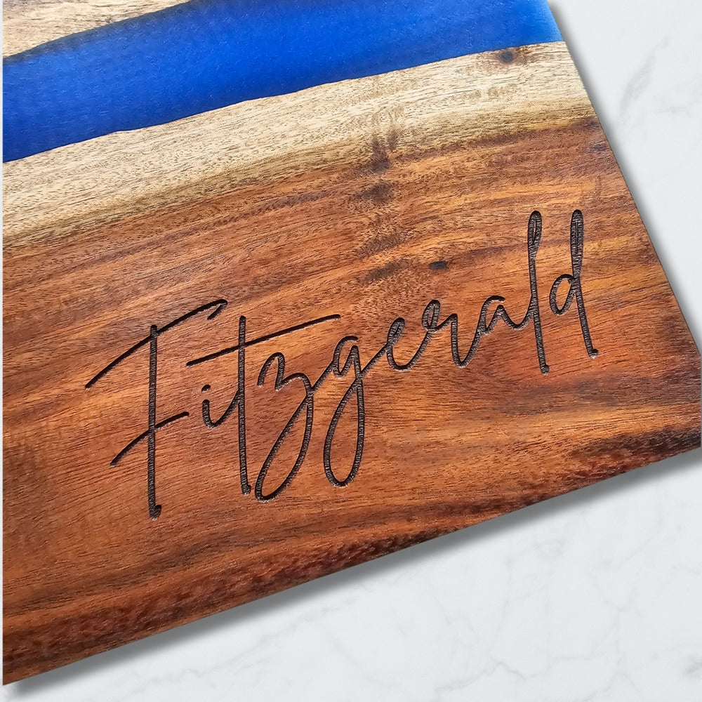 close up of wooden charcuterie board with resin inlay and last name 'Fitzgerald' engraved in the bottom right corner
