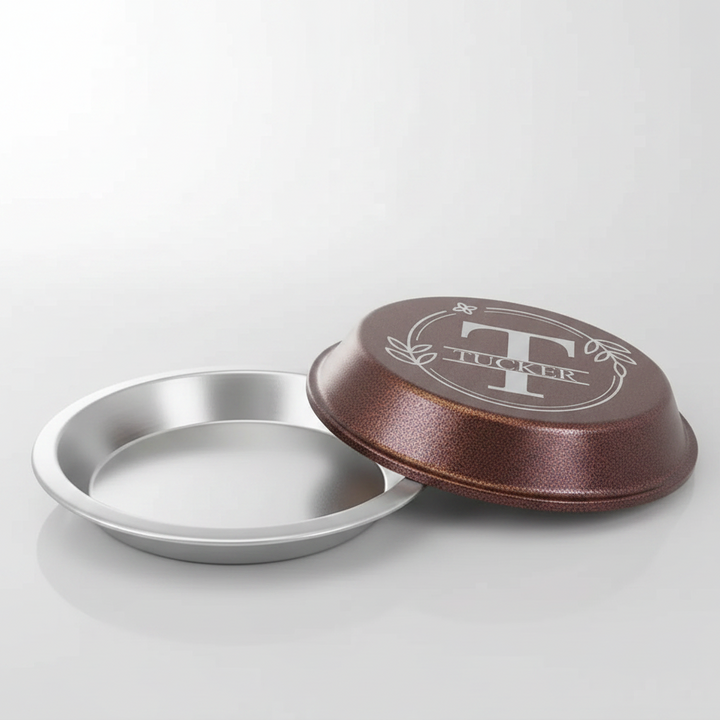Aluminum pie pan with copper lid with a initial and name monogram in a wreath design on a white background