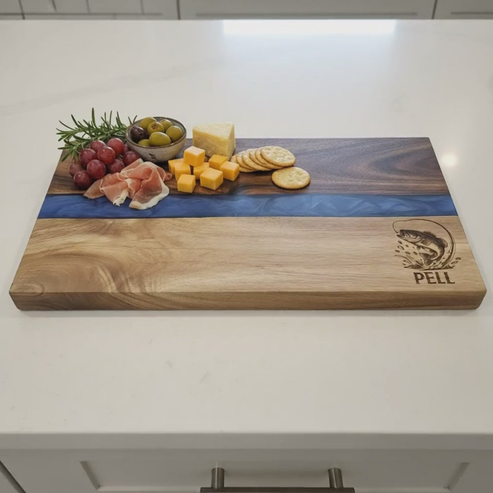 video: wood charcuterie board with fishing logo and name engraved in bottom right corner showing details of laser engraving