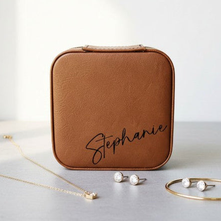 Brown jewelry box with 'Stephanie' engraving, necklace, earrings, and bracelet on a light surface.