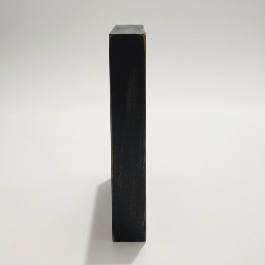 A close-up side view of a black 6x6 inch sign showing the 1 inch thickness