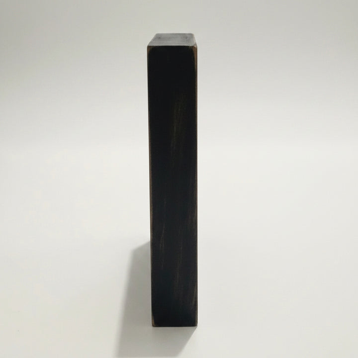 A close-up side view of a black 6x6 inch sign showing the 1 inch thickness