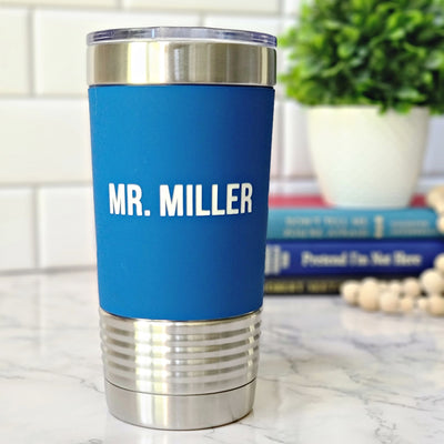 Blue stainless steel tumbler with silicone sleeve. A middle school teacher name is laser engraved in white on the blue silicone sleeve.