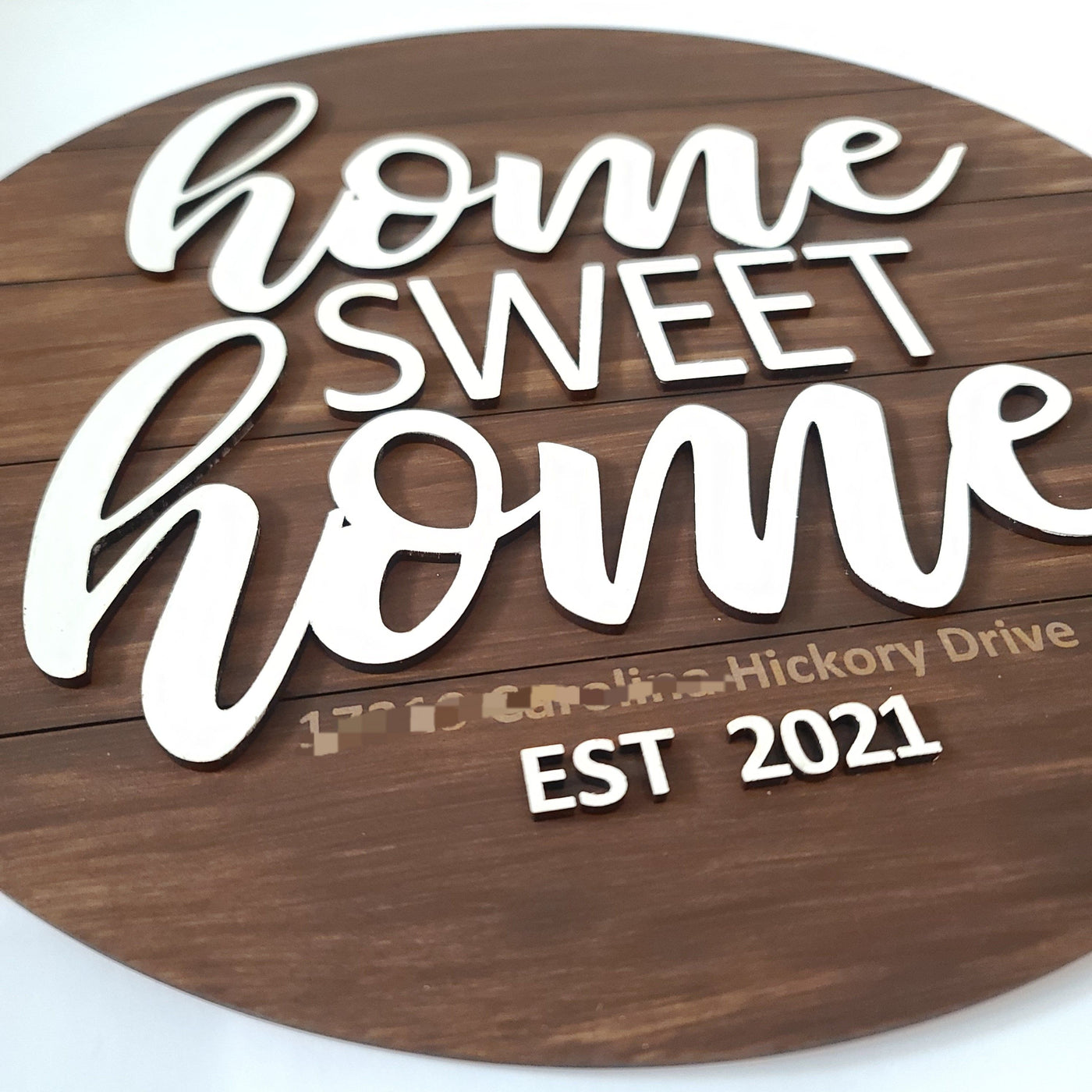 Home sweet home laser cut round shiplap sign with engraved address and established year. Round shiplap painted brown with white script and print letters saying "home sweet home". White letters are attached on top of round shiplap creating a 3D element.
