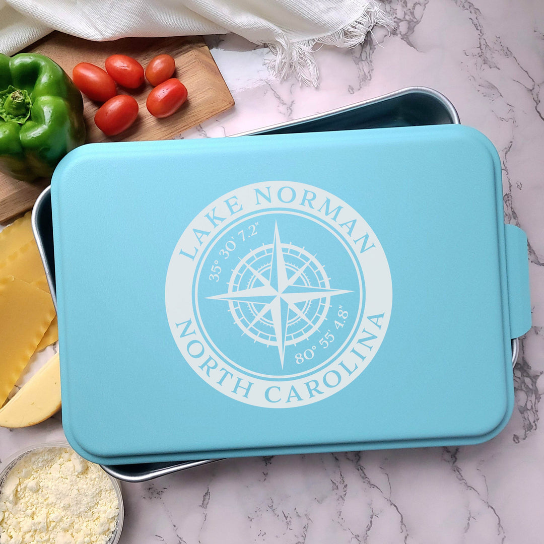 Metal casserole dish with teal lid and 'Lake Norman North Carolina' compass with coordinates design engraved in center of lid.