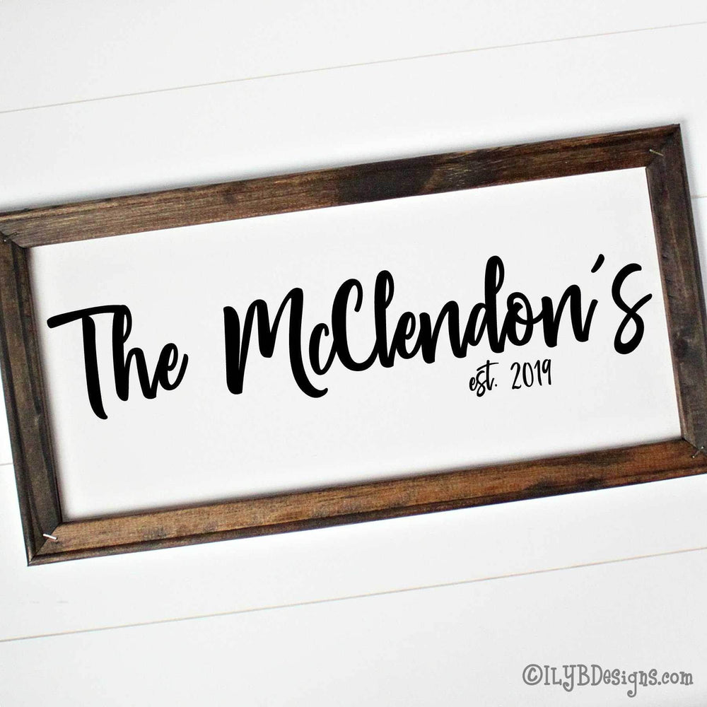 Canvas sign with 'The McClendon's est. 2019' black text on a white canvas with a brown wood frame.