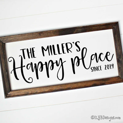 Dark walnut stained 20"x10" frame on a white canvas with black words in a mix of script and print fonts. It reads, "The Miller's Happy place since 2019." The design is placed horizontally on the sign.