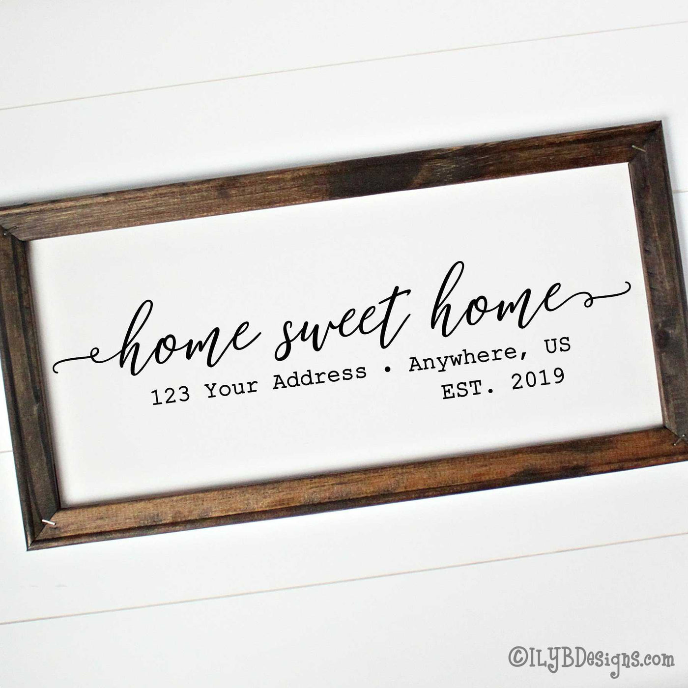 Home sweet home written in black script with an optional address and established year below. Design is on a white canvas framed with a dark walnut stain frame. The frame measures 20"x10" and design is placed horizontally.