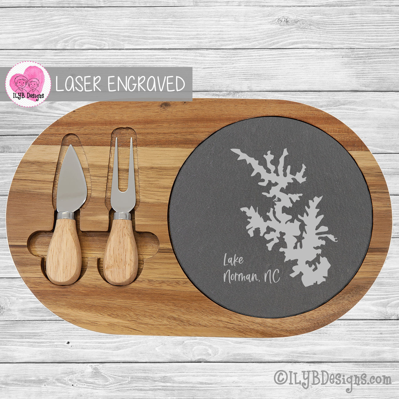 Oval solid acacia wood cheese board with round slate insert and 2 serving tools (a knife and fork). The slate is laser engraved with the silhouette of Lake Norman, NC along with the words in script.